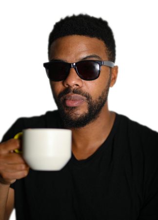 Man wearing sunglasses holding a white coffee cup.