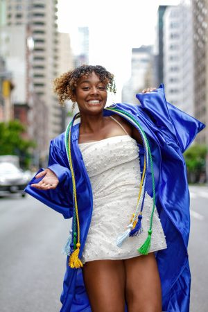 Young woman joyfully celebrating graduation in a blue cap and gown.