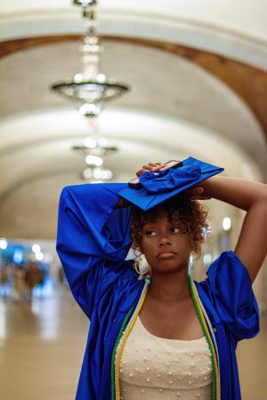 Fashionable woman in a blue outfit adjusting her hat indoors.