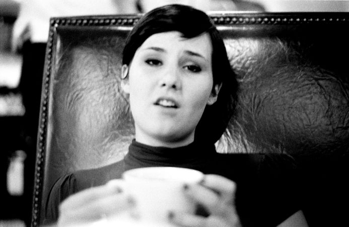Black and white photo of a woman holding a cup, looking thoughtful.