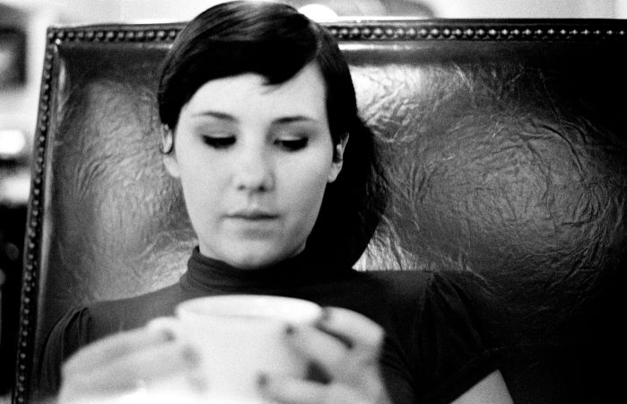 Black and white photo of a woman looking down at a cup.
