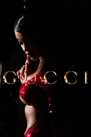 Woman in red latex outfit posing in front of illuminated Gucci sign.