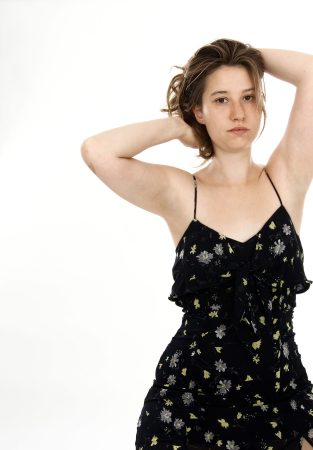 Young woman in a black floral dress posing against a white background.