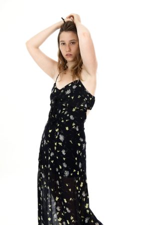 Young woman in a black floral dress posing with arms raised.