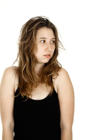 Young woman with wavy hair wearing a black tank top looking to the side.