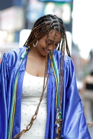 Woman smiling with braided hair and colorful streaks in a blue robe.